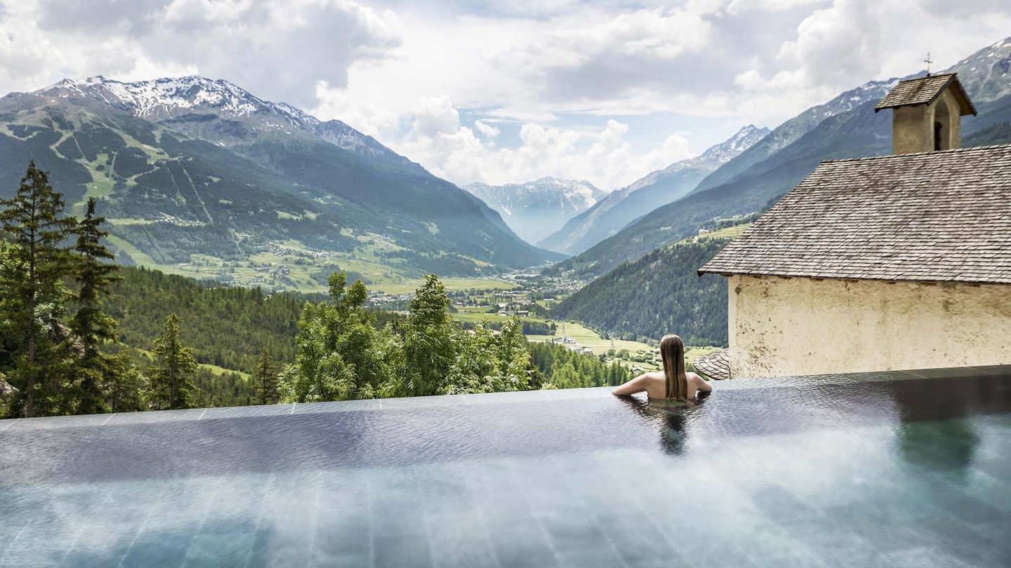 Pure relaxation against a breathtaking backdrop: An infinity pool overlooking the snow-capped peaks of the Alps, nestled next to the historic walls of the Bagni Vecchi.