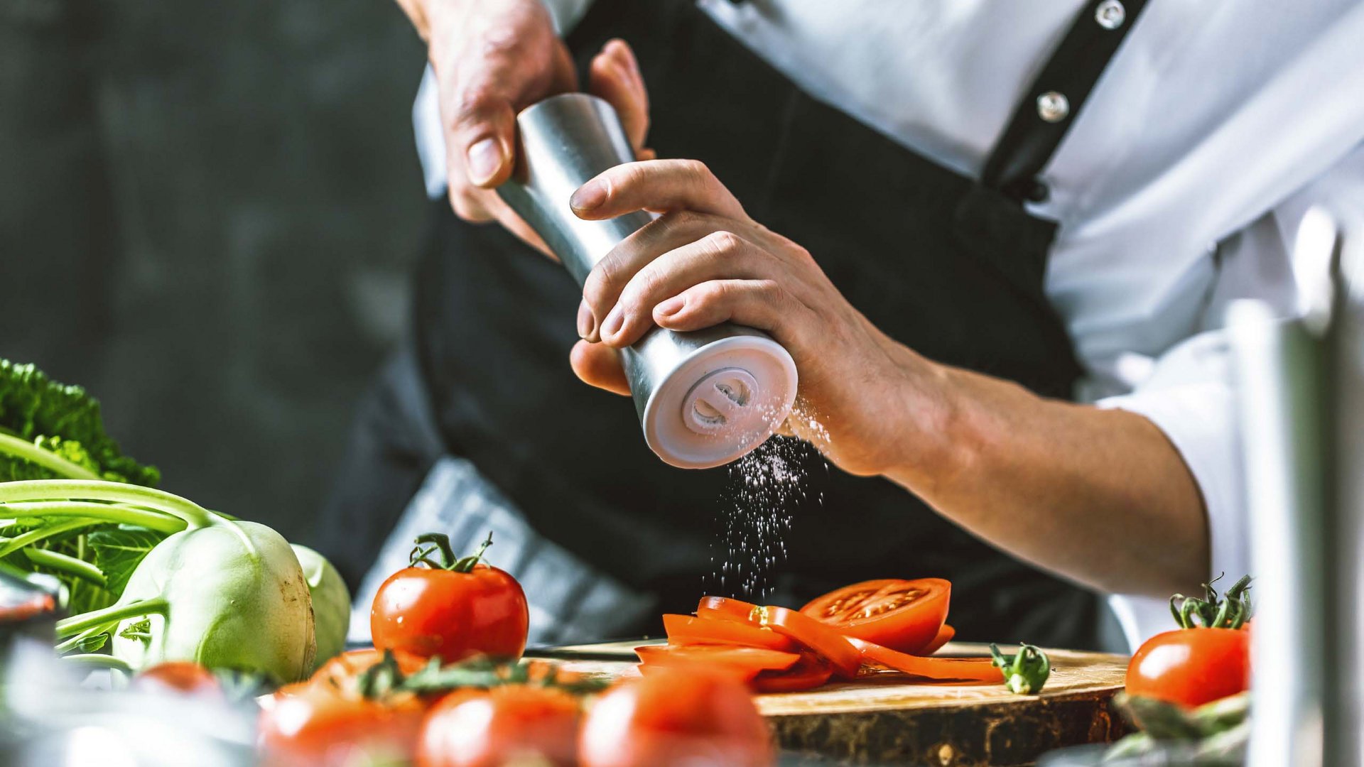 A chef at Hotel Bella Vista meticulously seasons fresh ingredients, showcasing the culinary dedication and quality of the hotel's kitchen.