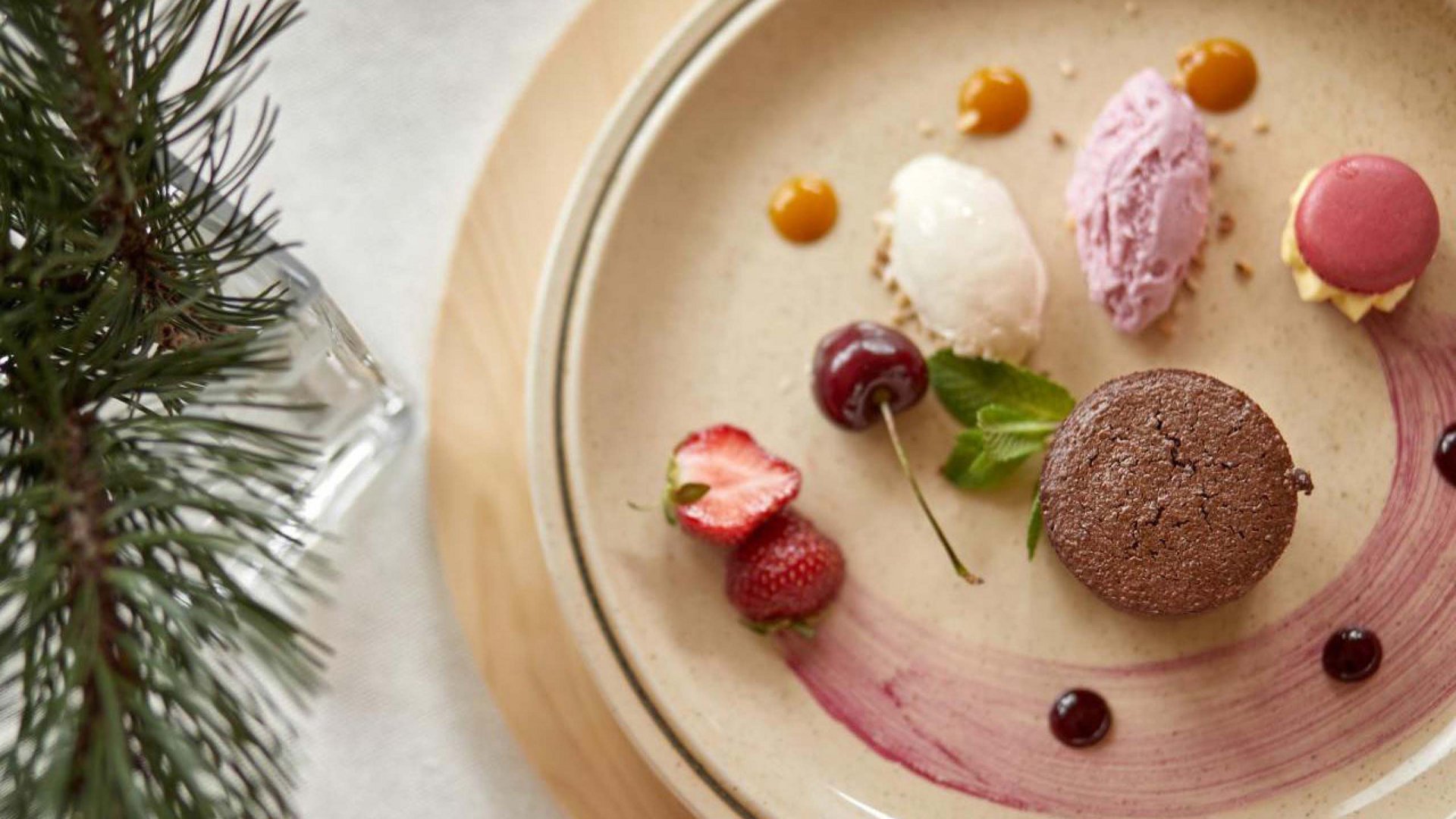 Artfully decorated dessert featuring an assortment of ice cream scoops and fresh fruits, served on a ceramic plate at Hotel Bella Vista.