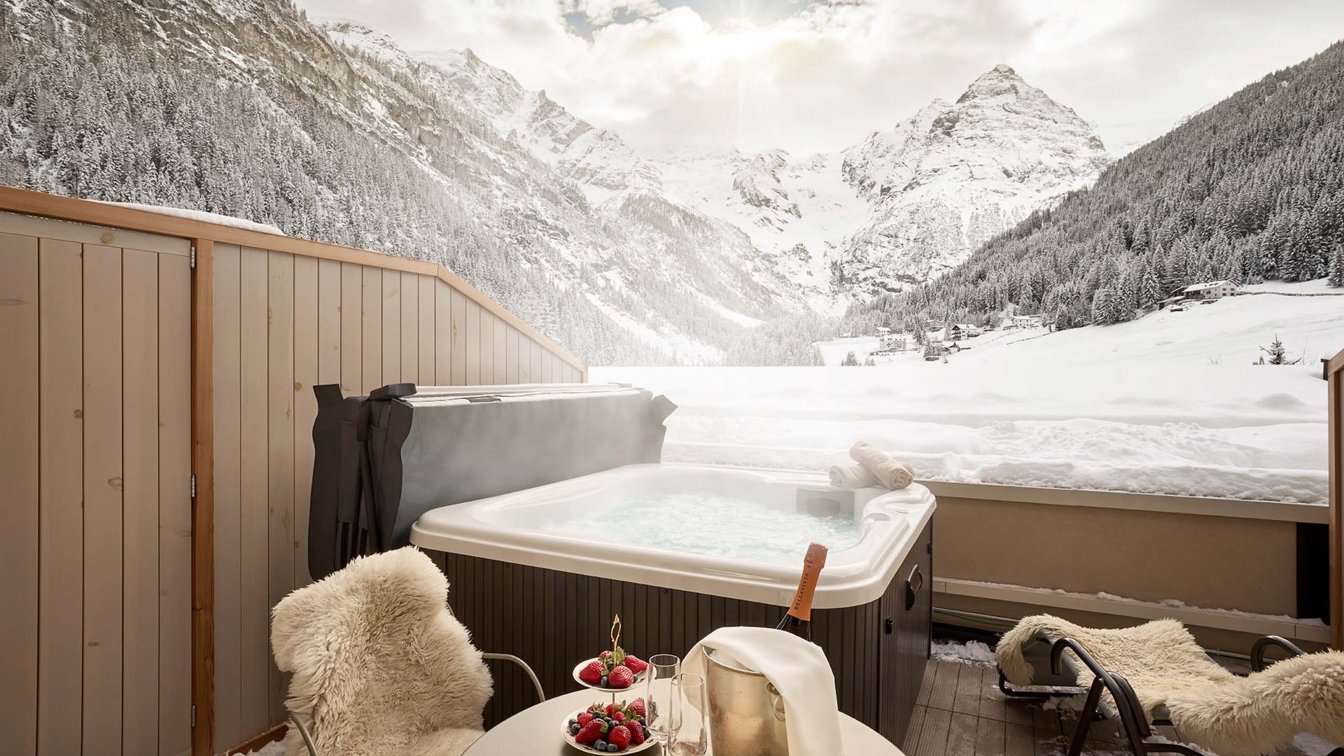 Winterliche Entspannung im Whirlpool des Hotel Bella Vista, mit Blick auf die verschneiten Alpengipfel und bereitgestellten Snacks.